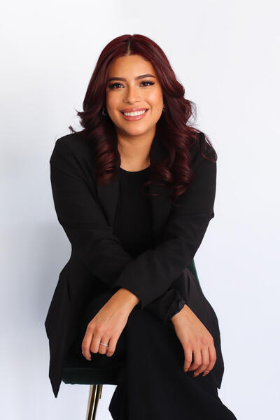 Ivana Hernandez sitting on a stool and smiling at the camera
